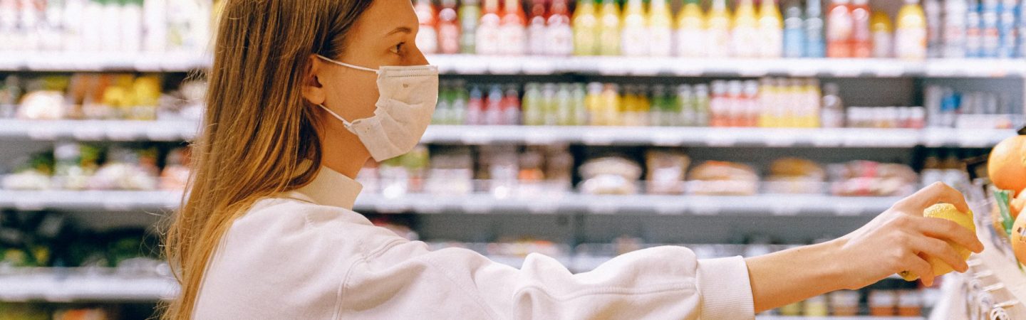 Woman shops in grocery store wearing facemask during COVID-19